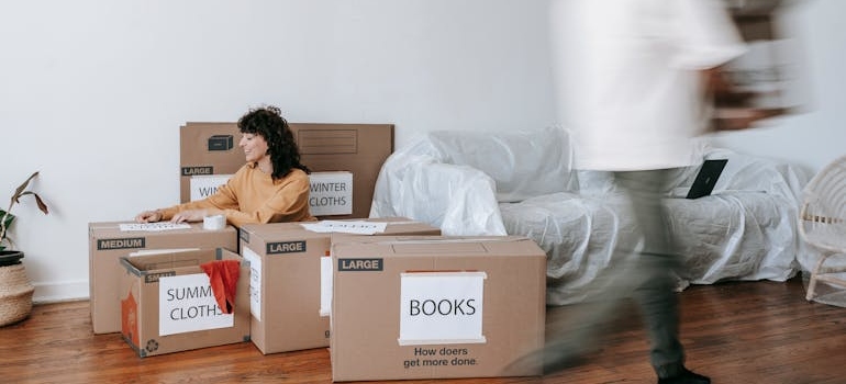 Woman Sitting On Floor Beside Packed Boxes showing how to pack for moving