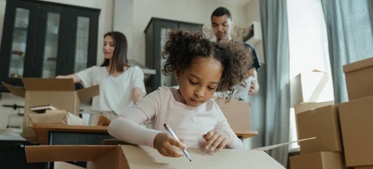Girl in White Long Sleeve Shirt Writing on a moving box