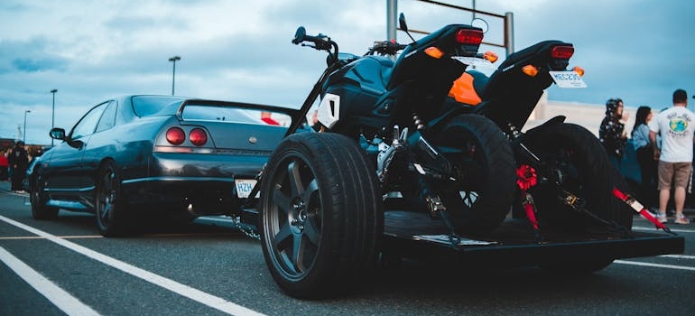 A car pulling atrailer with two bikes while shipping a motorcycle across country