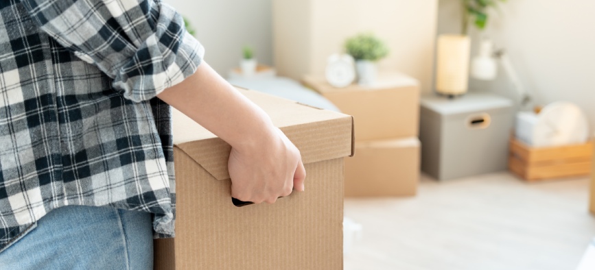 Moving house, relocation. Woman hold carton box contain equipment for new condominium, inside the room was a cardboard box containing personal belongings and furniture. move in the apartment