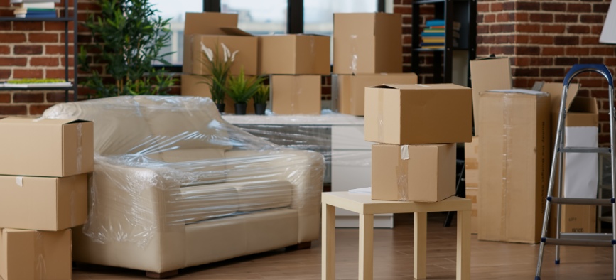 No people in empty living room apartment with carton boxes on stack, moving cardboard storage packaging in new household. Nobody in relocation property with interior furniture cargo.